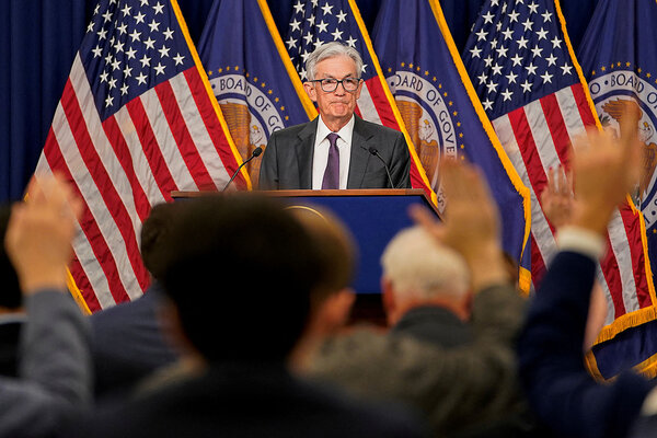 Standing in front of a wall of flags, U.S. Federal Reserve Chair Jerome Powell answers questions from reporters.